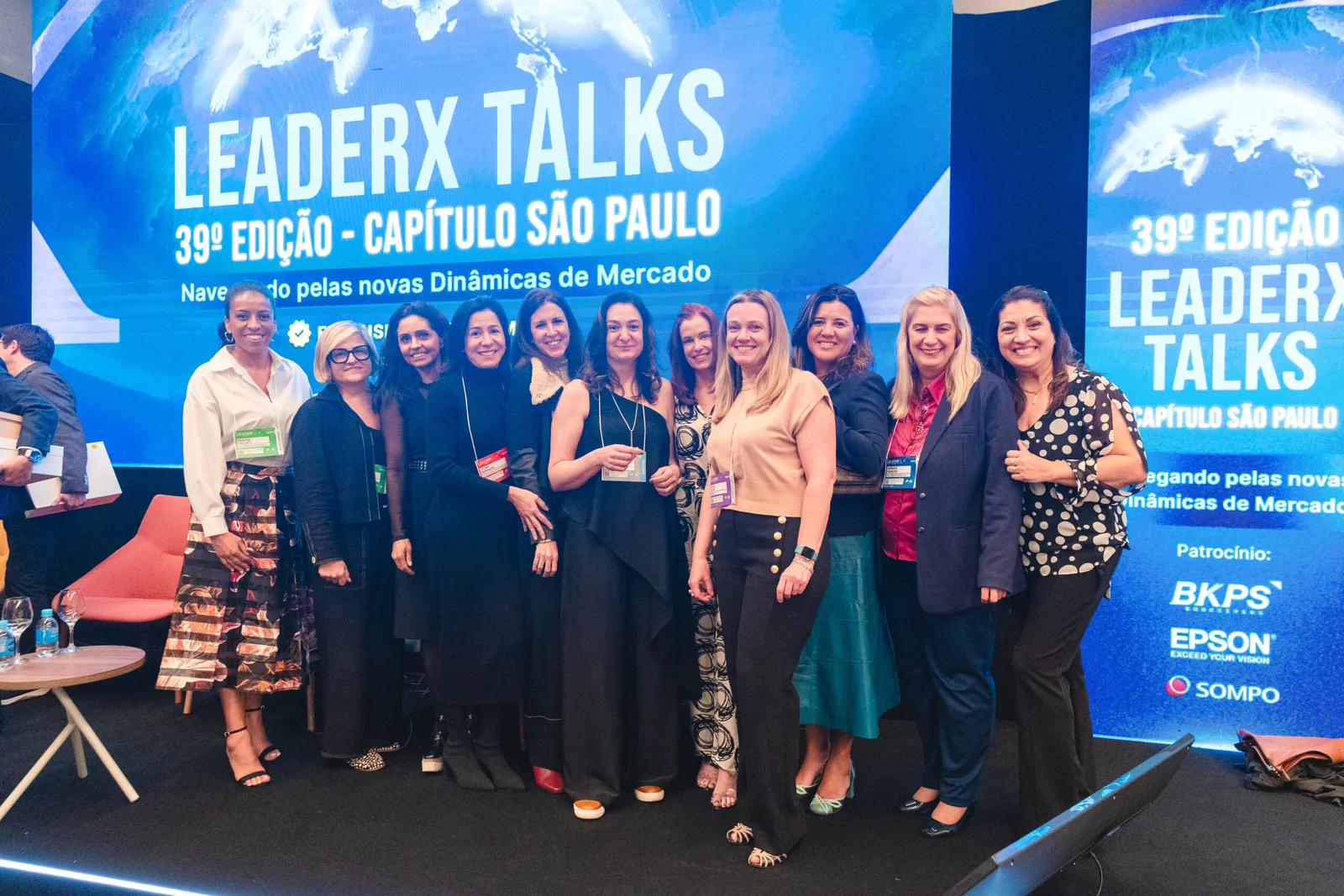 Grupo de líderes diante do letreiro do LeaderX Talks
